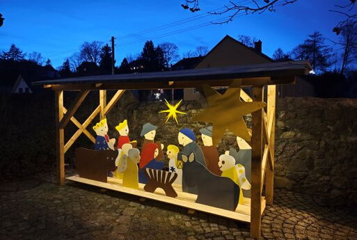 Krippe im Kirchhof der Kirche in Cossebaude: Die Figuren sind Laubsägearbeiten, die von Kindern bemalt worden sind.