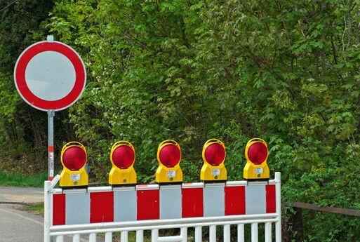 Links im Bild: Verkehrsschild "Einfahrt verboten" | Rechts daneben: Baustellenabsperrung mit fünf Warnleuchten