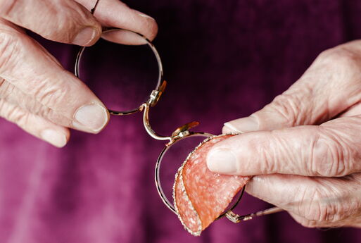 Ein älterer Mensch versucht, seine Brille mit einer Scheibe Salami zu reinigen.